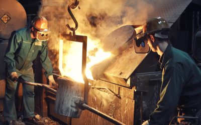 Group of workers in a foundry at the melting furnace - production of steel castings in an industrial company