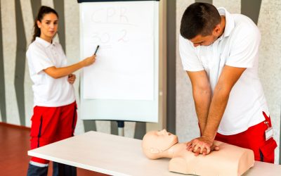 CPR class with instructors talking and demonstrating firt aid, compressions ans reanimation procedure. Cpr dummy on the table.